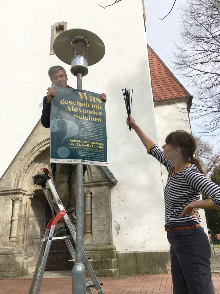 Die Projektbeteiligten Julia Roesler und Markus Müller beim Anbringen von Plakaten für die Eröffnungsveranstaltung im April 2022