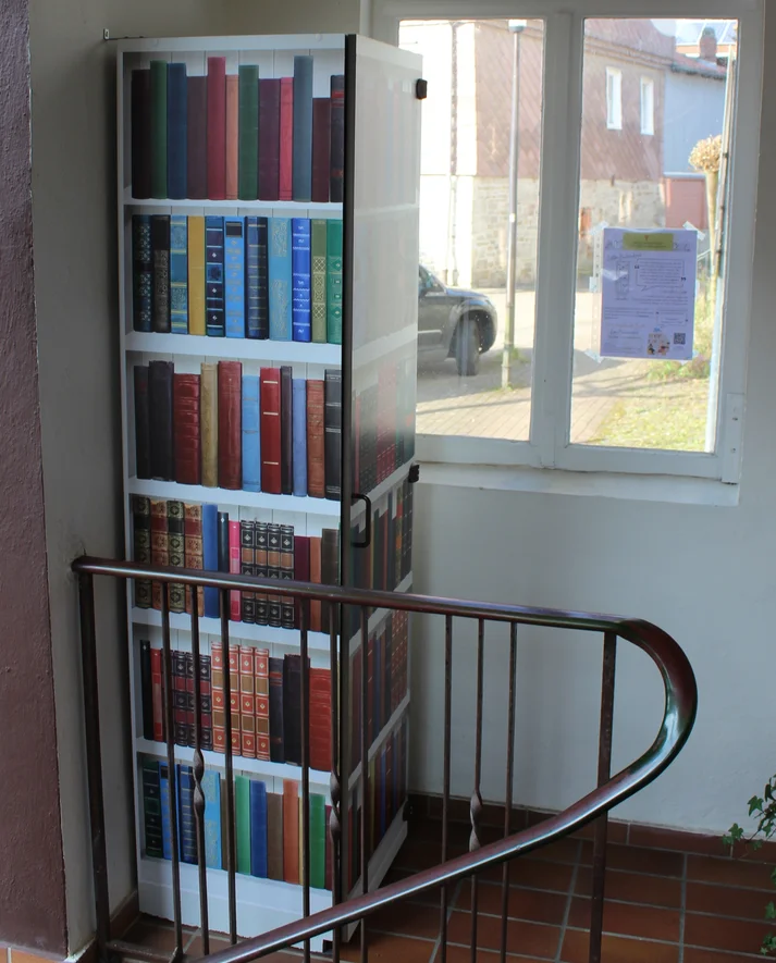Bücherschrank im überdachten Vorraum der örtlichen St. Barbara Apotheke