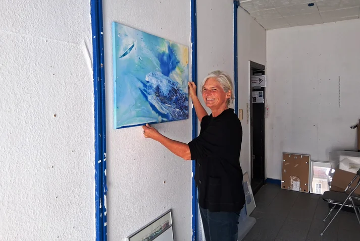 Hiltrud Esther Menz hängt lachend ein Bild auf