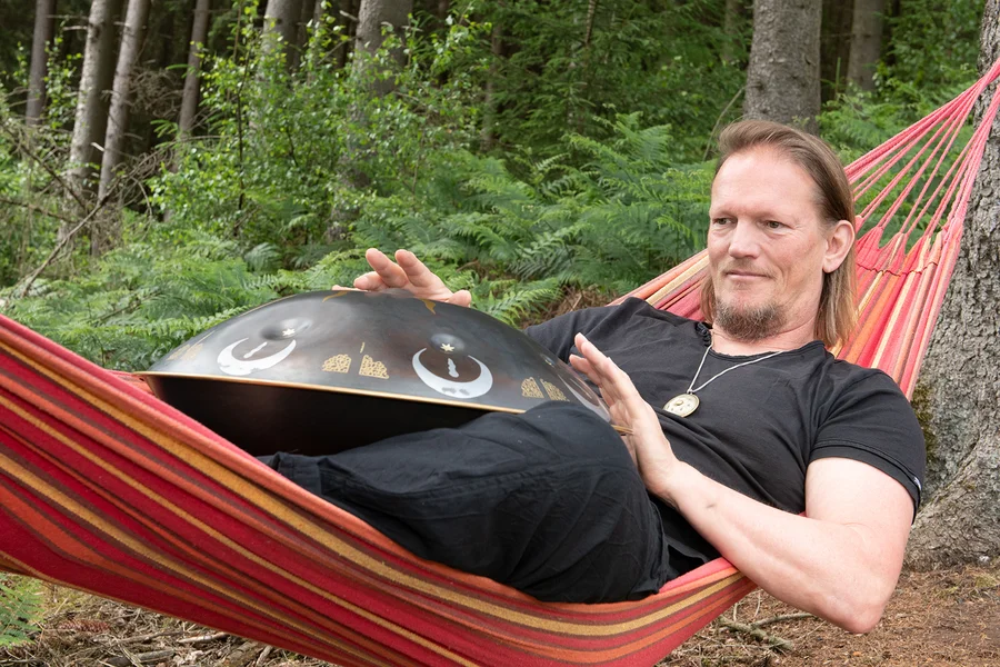 Rolf Predotka (alsia Hangklang) spielt in einer Hängematte liegend auf einer Hangdrum.