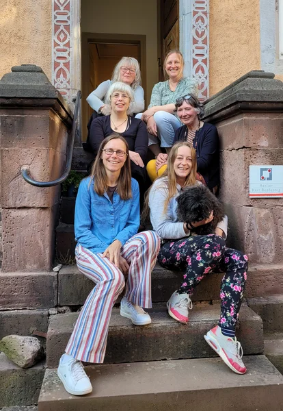 6 Organisatorinnen des Atelier Repfennig sitzend auf Treppe vorm Atelier