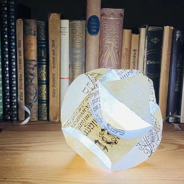 Leuchtende Papierkugel in einem Bücherregal