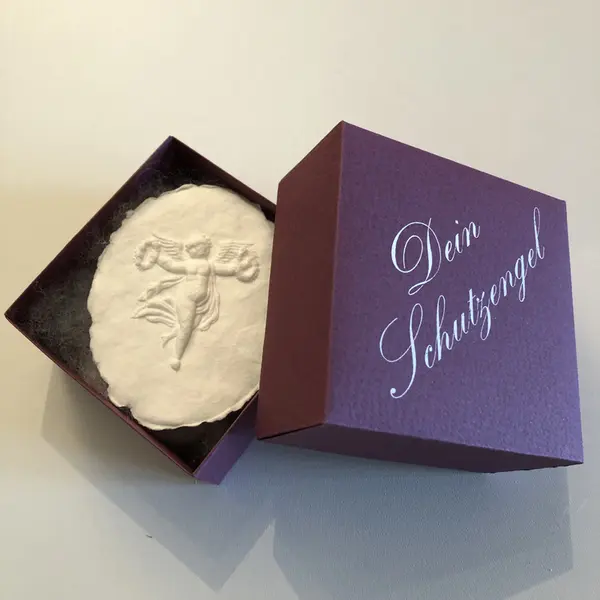 Engelmotiv aus Papier in einer weinroten Schachtel
