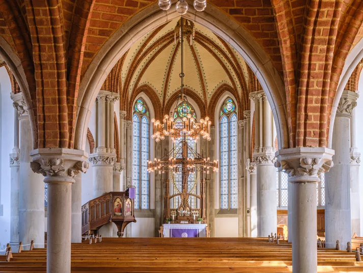 Innenaufnahme Martinskirche. Blick auf den Altar durch zwei Säulen, mittig hängt ein Kronleuchter.