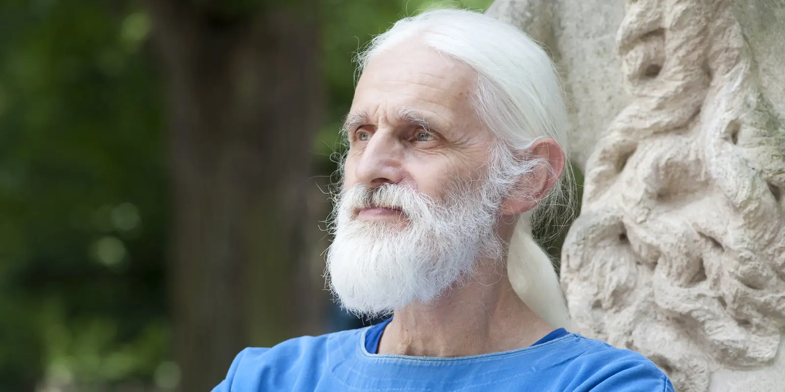 Joachim Eriksen lehnt an einer Steinskulptur und blickt in die Ferne