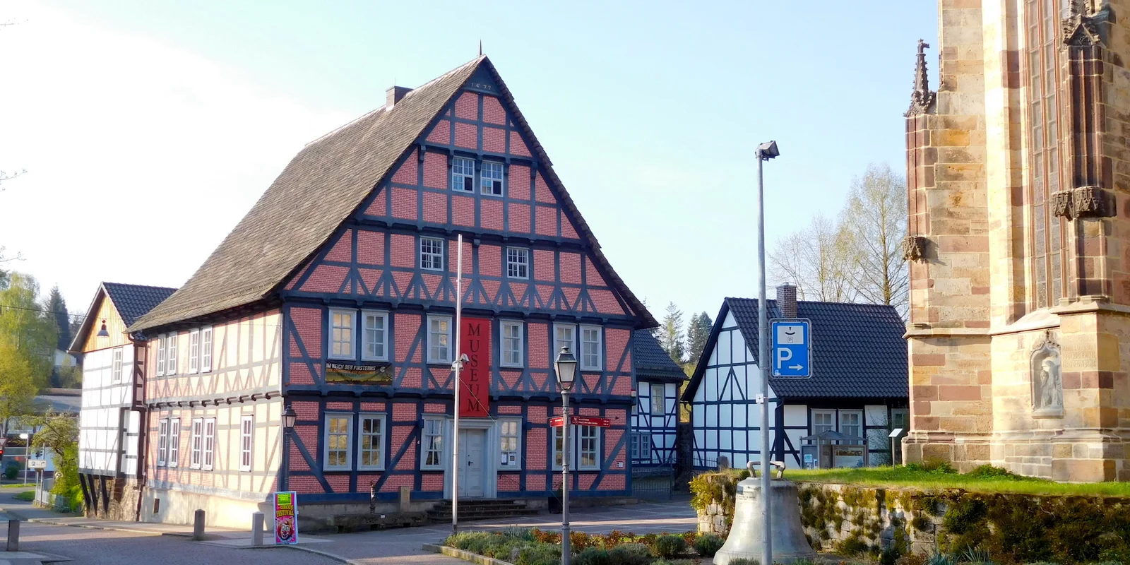 Ein großes Fachwerkhaus mit rot gemauerten Gefachen, über dem Eingang eine rote Fahne mit der Aufschrift Museum