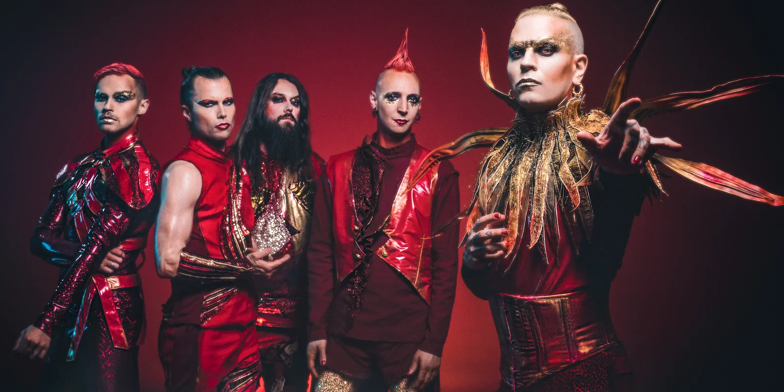Die Bandmitglieder von Lord of the Lost vor rotem Hintergrund in rot-goldenen Kostümen.