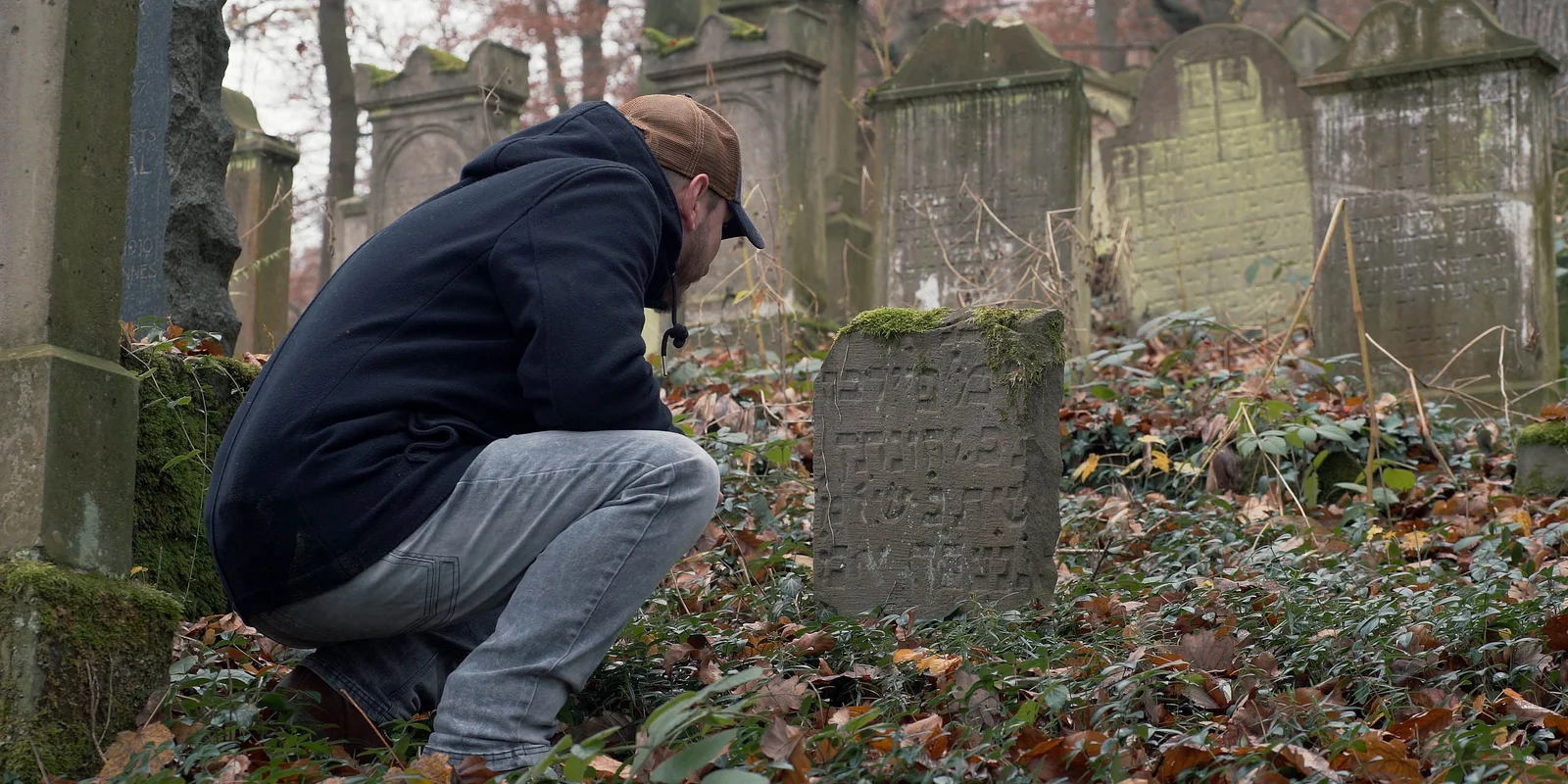Christian Riemenschneider kniet vor einem Grabstein mit hebräischer Inschrift