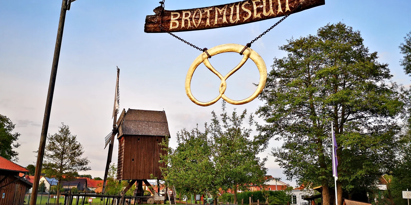 Das Schild des Europäischen Brotmuseums mit der historischen Mühle im Hintergrund