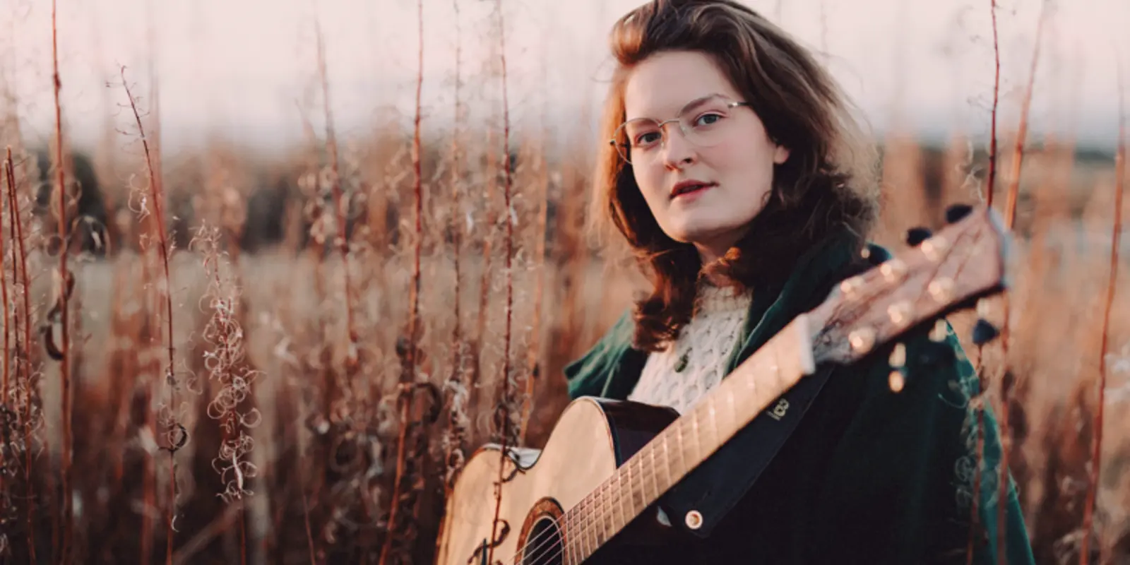 Iona Lane mit Gitarre im Kornfeld