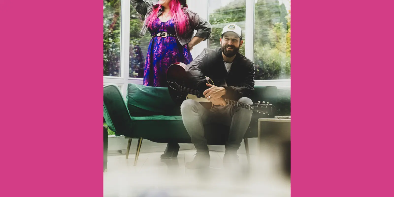 Das Duo befindet sich vor einem Fenster, die Sängerin stehend, der Gitarrenspieler sitzend