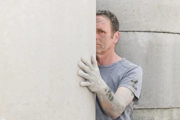 Andreas Jeßing steht halb verdeckt hinter einer Betonwand, seine dreckige, verstaubte Hand hat er auf die Wand gelegt.