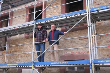 Fabian Froböse und Friedhelm Honig stehen auf einem Baugerüst vor dem Ratskeller Moringen