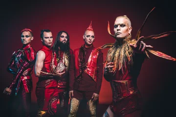 Die Bandmitglieder von Lord of the Lost vor rotem Hintergrund in rot-goldenen Kostümen.