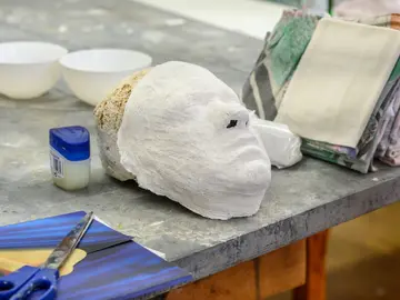Eine Maske liegt mit Werkzeug auf dem Tisch