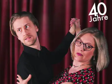 Ein Mann und eine Frau in Tanzpose vor einem Vorhang