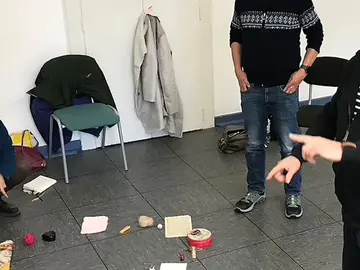 Seminarteilnehmer*innen sitzen vor Objekten auf dem Boden