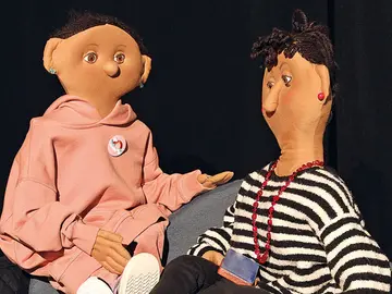 Zwei Puppen sitzen auf einem Sofa