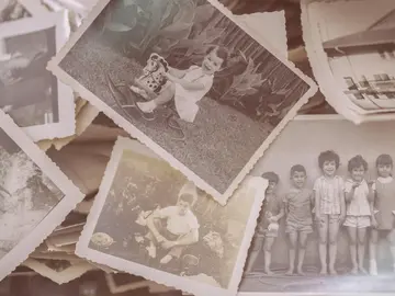 Mehrere alte Schwarz-Weiß-Fotografien mit gezackten Rändern, die Kinder beim Spielen, Familienmomente und Landschaften zeigen.
