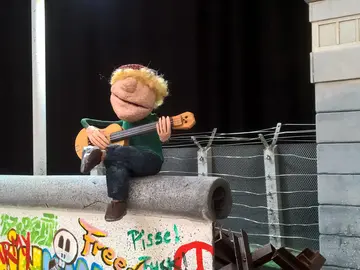 Szenenfoto Gitarrenspieler auf der Mauer