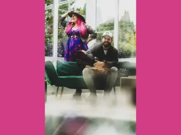 Das Duo befindet sich vor einem Fenster, die Sängerin stehend, der Gitarrenspieler sitzend