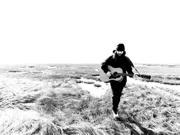 Jared Hart am Strand mit Gitarre