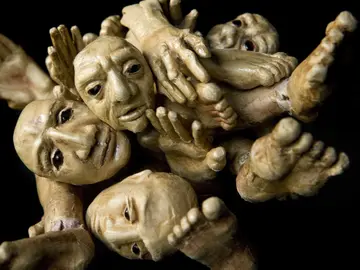 Mehrere ineinander verschlungene Puppenfiguren mit ausdrucksstarken Gesichtern und ausgestreckten Händen und Füßen vor schwarzem Hintergrund. Mehrere ineinander verschlungene Puppenfiguren mit ausdrucksstarken Gesichtern und ausgestreckten Händen und Füßen vor schwarzem Hintergrund.