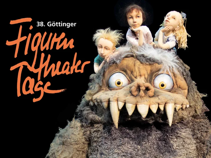 Auf schwarzem Grund links der Schriftzug "Figurentheatertage", daneben eine Monster-Figur mit zotteligem grauen Felld und riesigen Zähnen, auf deren Kopf drei Kinderfiguren sitzen und träumerisch in die Gegend schauen. 