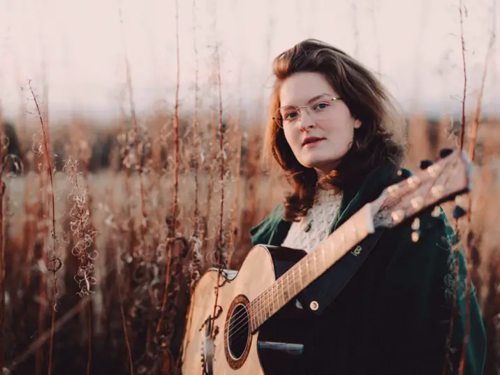 Iona Lane mit Gitarre im Kornfeld