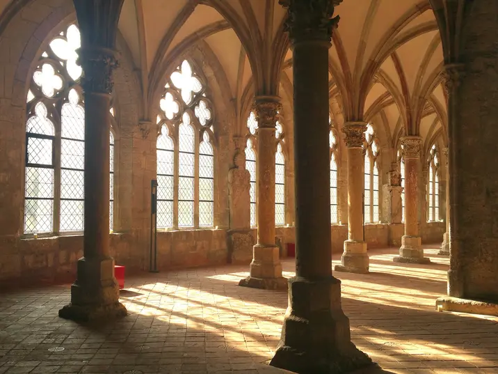 Durch die Maßwerkfenster fällt das goldene Abendlicht in den nördlichen Kreuzgang.