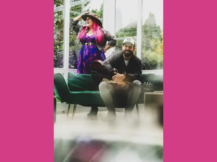 Das Duo befindet sich vor einem Fenster, die Sängerin stehend, der Gitarrenspieler sitzend
