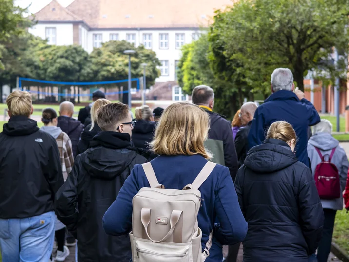 Besuchende der Gedenkstätte bei einem Rundgang im Innenhof des ehemaligen KZ-Geländes.